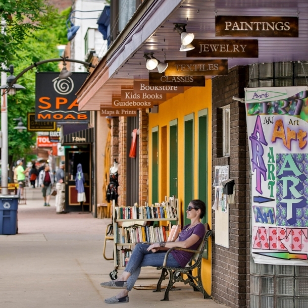 Image of a street in Downtown Moab with a person seated on a bench