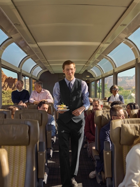 Image of host smiling as they hold a plate of food to serve to guests on the train