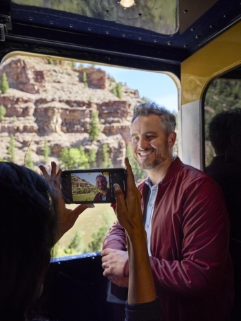 Image of a guest taking a picture of another guest with their phone against the canyon background