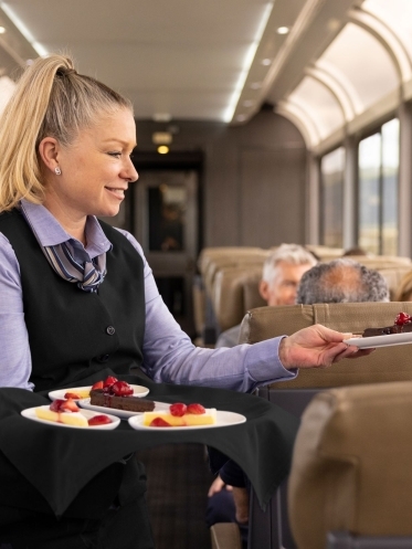 Image of host serving food to guests aboard the train.